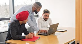 Three male students working on a laptop